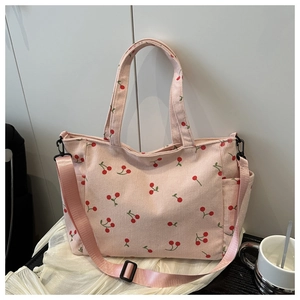 Gros plan du sac cabas en velours côtelé rose avec motifs cerises et bandoulière