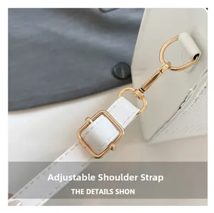 Detail view of white leather shoulder strap with gold metal buckle and stitching