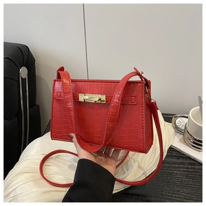 Close-up of red crocodile pattern handbag featuring a gold metallic twist lock