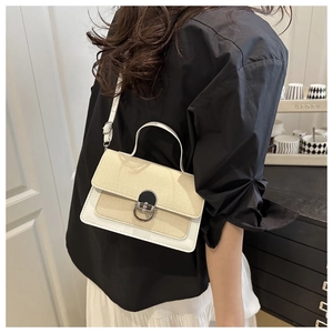 Detail of elegant woven and leather shoulder bag with circular silver buckle closure