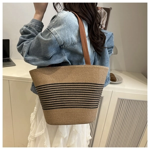 Lifestyle shot of large striped straw tote bag worn over the shoulder by a woman