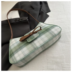 Detail of green and white checkered shoulder bag with brown leather bow and strap