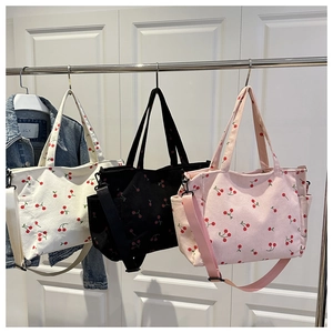 Trois sacs cabas en velours côtelé à imprimé cerise avec bandoulières sur des cintres