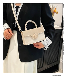 Detail of cream leather handbag with woven handle and gold flower magnetic buckle