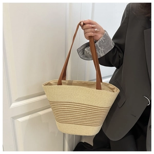 Detail of hand-woven straw tote bag with brown handles and light fabric lining