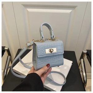 Close-up of light blue crocodile embossed leather mini bag with golden metal twist lock