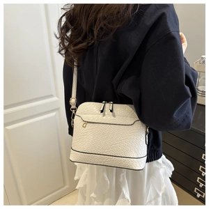 White shell bag with crocodile texture pattern and gold zipper detail shown on shoulder