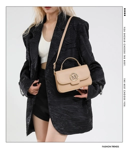 Detail of light beige crossbody bag with metal M letter logo and smooth leather texture