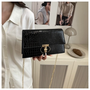 Detail of black crocodile pattern crossbody bag with gold lock and chain strap