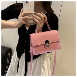 Detail of pink patchwork crossbody bag with woven texture and vintage metal ring lock