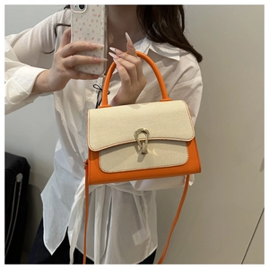 Detail of a two-tone contrast handbag in orange and beige with a gold metallic buckle