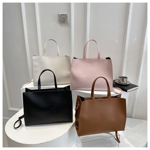 Macro display of minimalist leather tote bags in four colors on a white podium