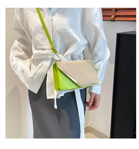 Détail d'un petit sac bandoulière vert fluo tissé porté par un mannequin