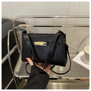 Detail of black crocodile texture PU handbag with luxury gold twist lock closure and strap