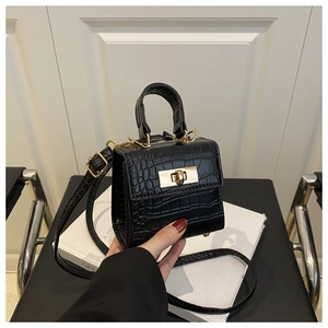 Close-up of black crocodile pattern leather texture with golden metal lock on handbag