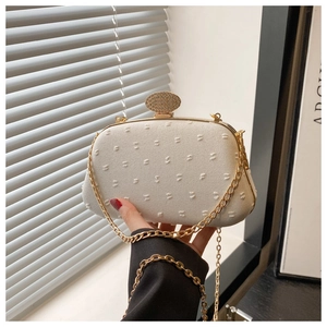 Macro detail of white textured evening clutch with sparkling diamond encrusted clasp and gold chain