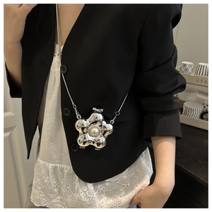 Detail einer silbernen metallischen Blumentasche mit Perle und feiner Metallkette