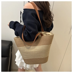 Detail of woven striped tote bag with canvas straps shown from a 45-degree angle