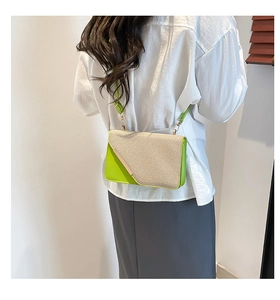 Détail d'un sac bandoulière en paille avec bordure en cuir vert fluo et boucles dorées