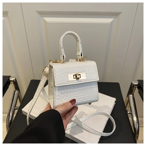 Close-up of white crocodile pattern mini handbag with golden clasp and detachable strap