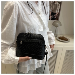 Detail view of black woven shell crossbody bag with dual zippers and adjustable strap