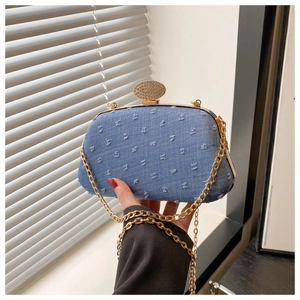 Detail of blue denim clutch bag with fringe texture and crystal gold clasp