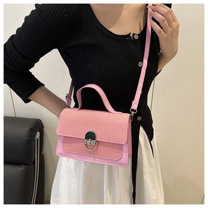 Detail of pink crossbody bag with woven texture flap and metallic turn-lock closure