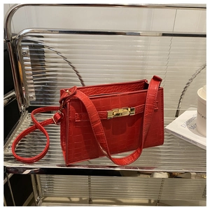 Detail view of red crocodile pattern shoulder bag with golden lock and textured finish