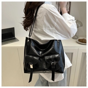 Close-up of black glossy tote bag with front pockets and silver metal buckle details
