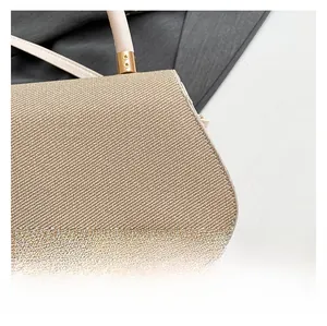 Detailed macro view of beige woven fabric texture and gold-tone hardware on the handbag