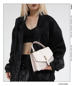 Detalle de bolso bandolera de cuero PU blanco con cierre dorado y asa superior elegante