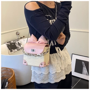 Detail of a straw and pink leather mini crossbody bag with a large bow and chain strap