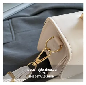 Detail view of white leather handbag with detachable strap and gold metal buckle