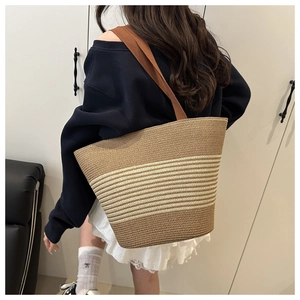 Detail of a large brown and beige striped woven tote bag with dark brown shoulder straps