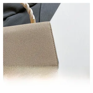 Detailed close-up of woven beige fabric and golden metal buckle on a fashion handbag