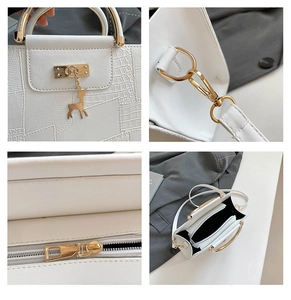 Detail of crocodile pattern texture with golden deer pendant and hardware on white bag