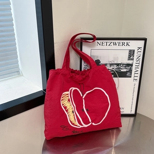 Red canvas tote bag with minimalist apple illustration on a metal table setting