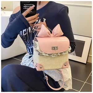 Detail of woven chain bag with pink bow accent and polished metal clasp lock