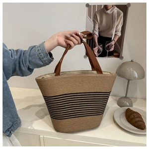 Detail of woven straw tote bag with black stripes in a cozy lifestyle setting