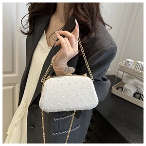 Macro detail of white textured evening bag with luxury crystal buckle and gold chain