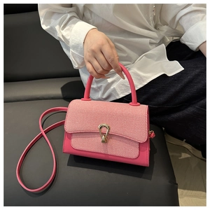 Detail of pink leather handbag with woven flap and gold U-shaped metal buckle closure