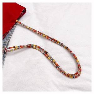 Detail of red canvas and blue denim tote bag with colorful woven shoulder strap