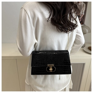 Detail of black crocodile texture shoulder bag with gold T-clasp and chain strap