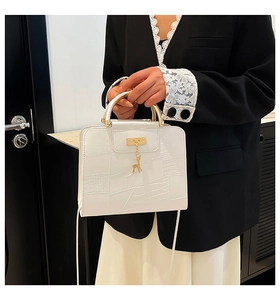 Detailed view of white patchwork handbag with gold deer charm and sleek metal handle