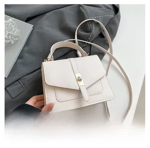 Detalle de elegante bolso de cuero crema con cierre metálico dorado y correa ajustable