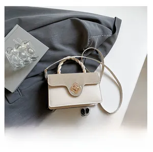 Detail of color-block flap bag with flower lock and phone for size comparison