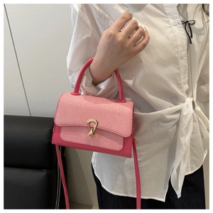 Detail of pink woven leather handbag featuring a stylish gold horseshoe buckle and handle