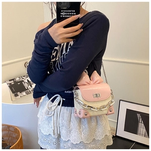 Close-up of mini pink bow crossbody bag featuring woven texture and chain strap
