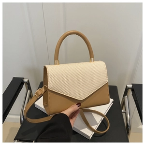 Détail du rabat tissé beige et sac en cuir camel avec des finitions dorées élégantes