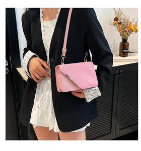 Detail view of pink leather crossbody bag with silver trim worn by a model in a modern home